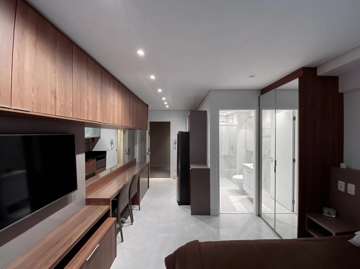 Estúdio planejado com painel de TV em madeira nobre, bancada de trabalho e closet com portas de vidro