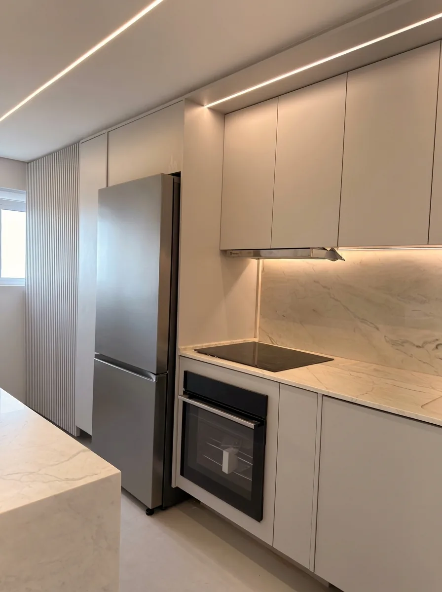 Cozinha planejada em tons off-white com cooktop, forno embutido e bancada em pedra