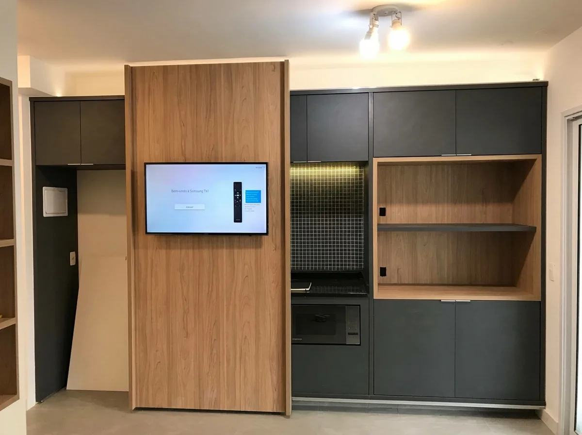 Hall de entrada com painel de madeira, TV embutida e cozinha em marcenaria escura com nichos