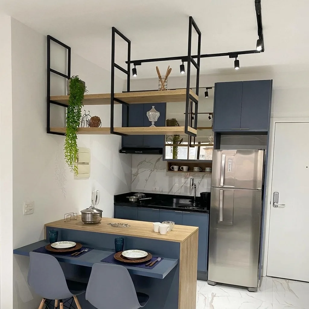 Cozinha compacta com marcenaria azul, prateleiras aramadas e mesa em madeira sob medida