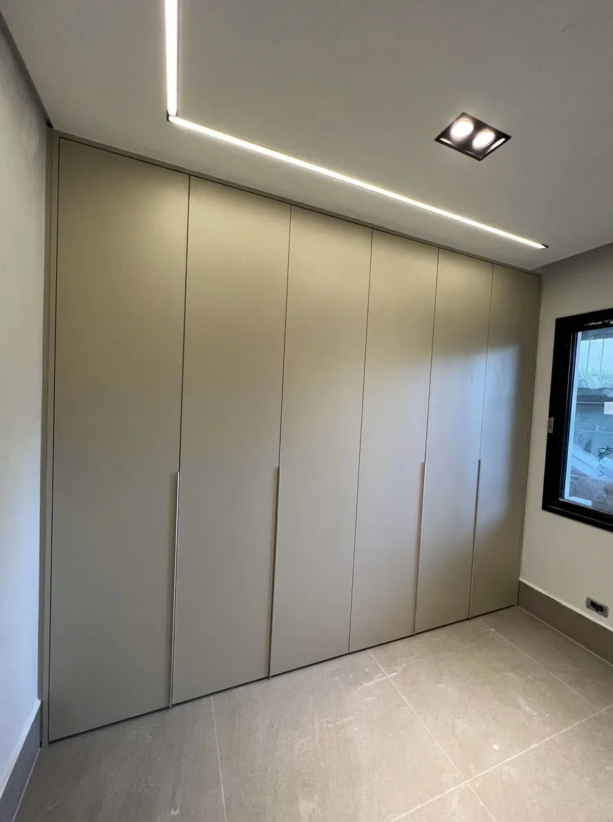 Armário planejado de piso a teto em tom neutro com iluminação linear embutida